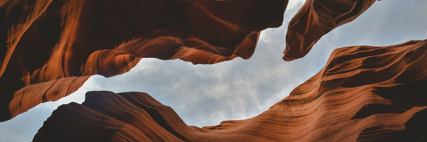 A view of the cloudy sky through the orange sandstone walls of Antelope Canyon